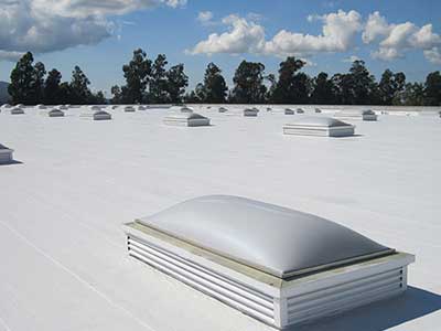 Overview of a typical flat white commercial roof with skylights dotted across it